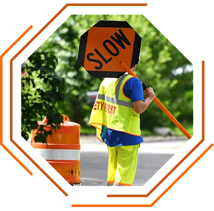 photo of a man in safety yellow gear holding an orange "Slow" sign for traffic management