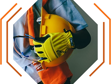 closeup photo of a man waring gloves and a safety vest, holding a hard hat tucked under his arm ("About KSK" decorative image)